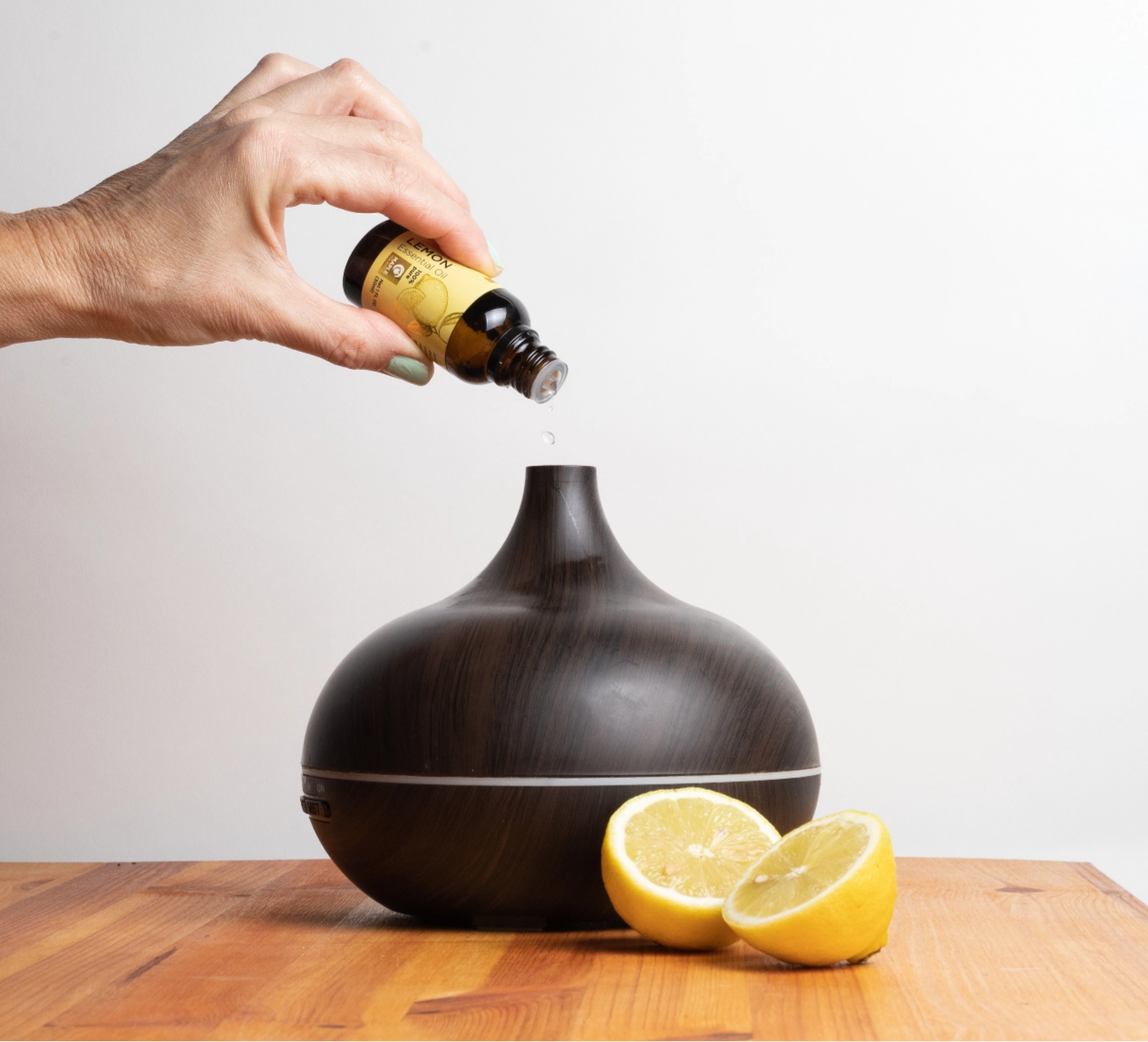 Maple Holistics Lemon Essential Oil being added to a diffuser 